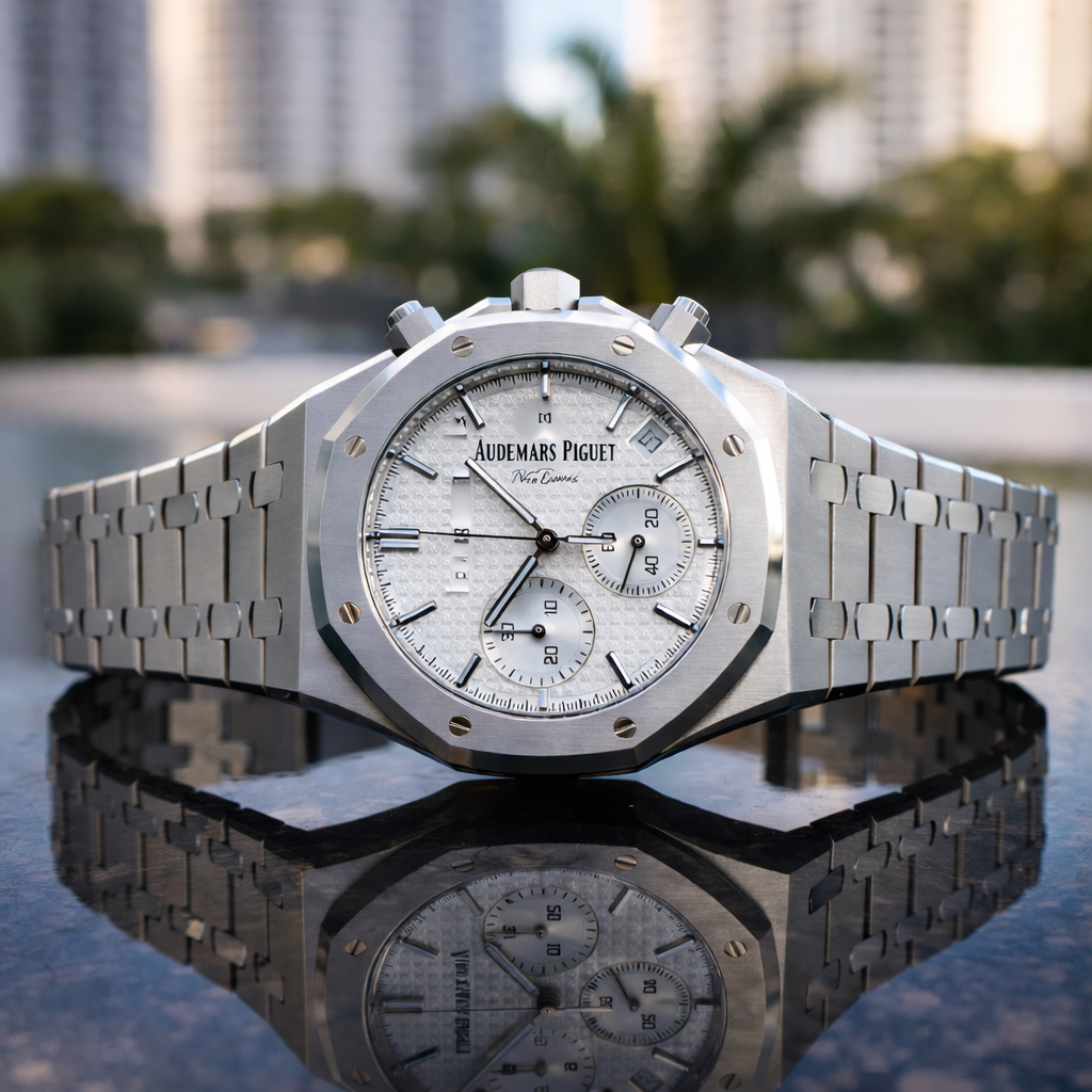 Audemars Piguet Royal Oak chronograph with silver dial resting on a reflective surface.