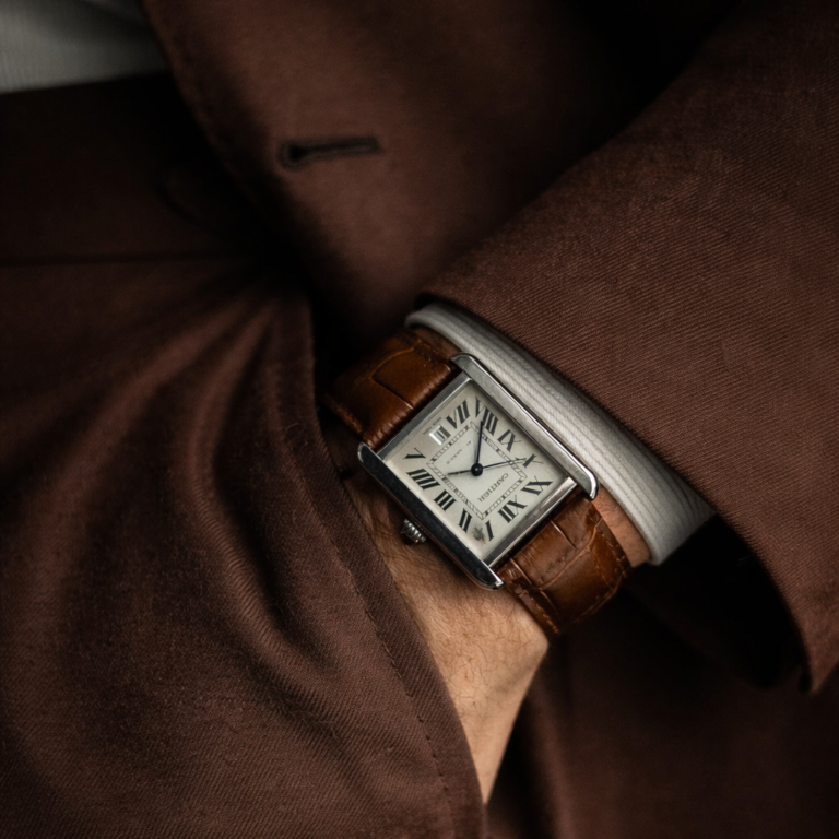 AI-generated image of a Cartier Tank watch with Roman numeral dial and leather strap, worn under a tailored suit sleeve.