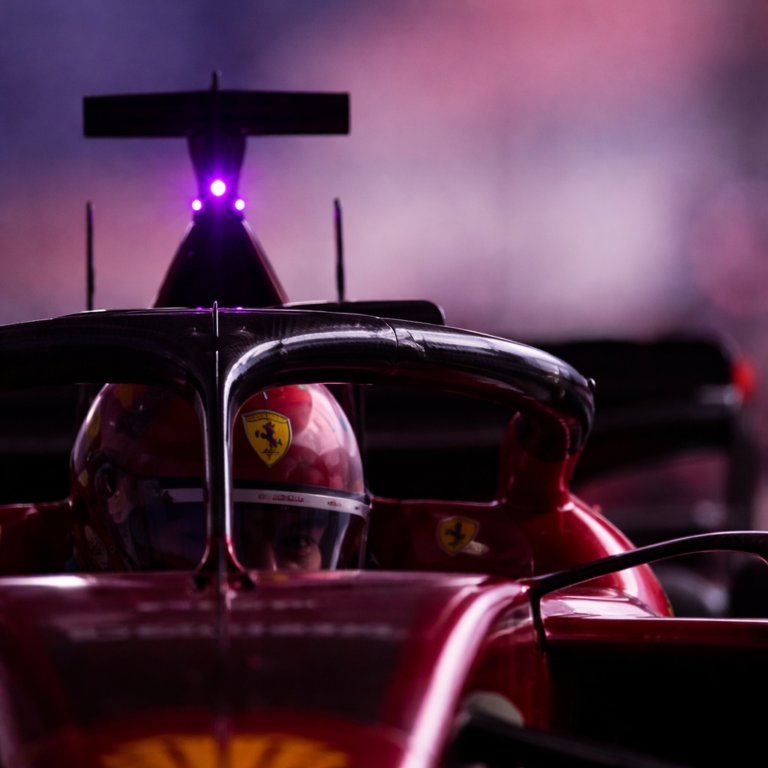 AI-generated close-up image of a Formula 1 driver inside the cockpit during a night race with glowing rear rain light and dramatic lighting.