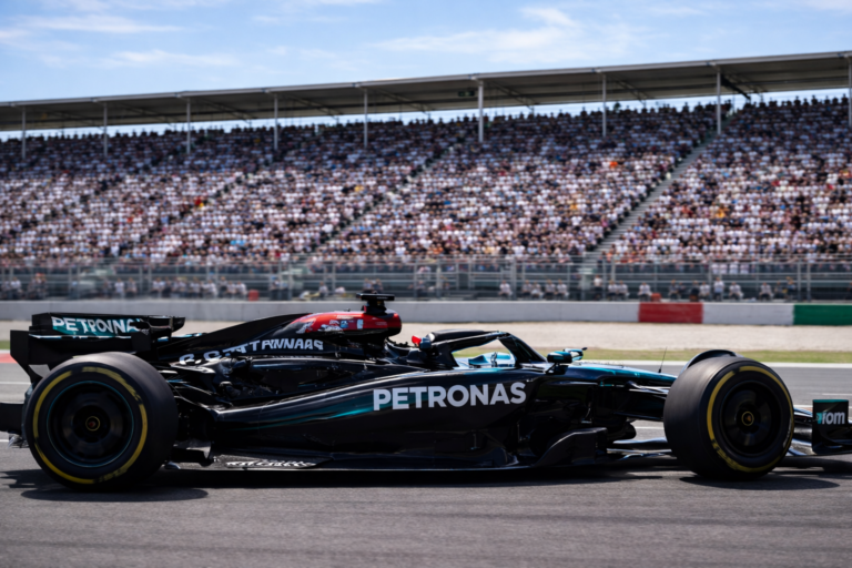 AI-generated editorial image of a Formula 1 race car speeding along a professional circuit with a packed grandstand of spectators in the background, captured in a sharp 4:3 motorsport scene.