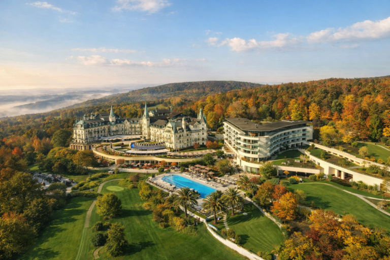 AI-generated aerial view of a luxury hillside resort resembling The Dolder Grand in Zurich with castle-style hotel, modern wing and landscaped grounds.