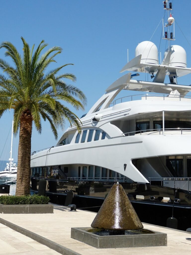 Large white superyacht docked at an exclusive marina with palm trees